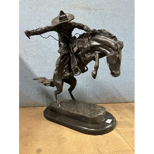 321 - After Frederic Remington, bronze figure of The Bronco Buster, on black slate socle