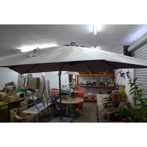 2207 - A large parasol umbrella with approximately 4m of coverage and a stone parasol base with four caster... 