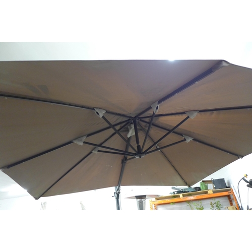 2207 - A large parasol umbrella with approximately 4m of coverage and a stone parasol base with four caster... 