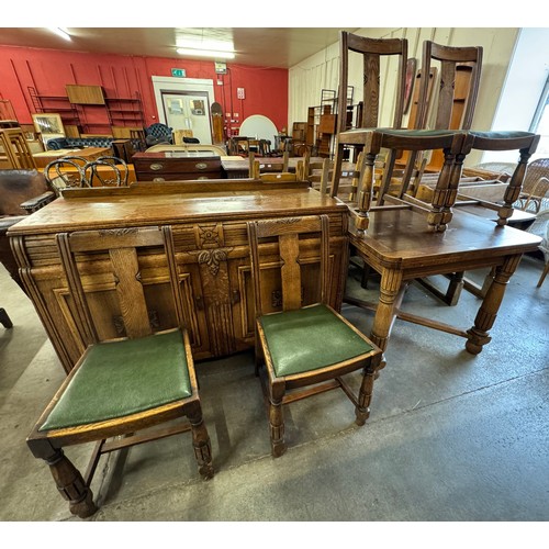 212 - An early 20th Century carved oak six piece dining suite, comprising; sideboard, draw leaf table and ... 