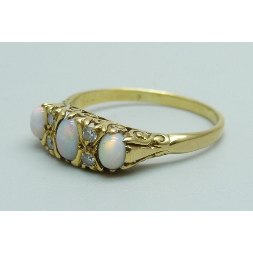 1032 - A yellow metal ring set with three opals and diamonds, 3.9g, Q