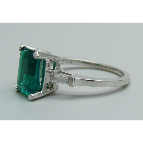 1163 - An 18ct white gold ring set with diamond shoulders and a synthetic emerald, 4.1g, L