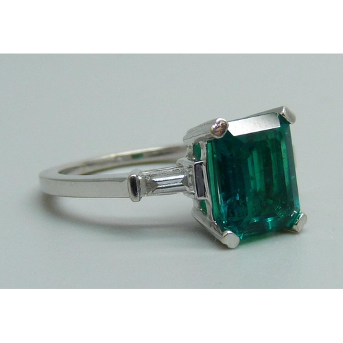 1163 - An 18ct white gold ring set with diamond shoulders and a synthetic emerald, 4.1g, L