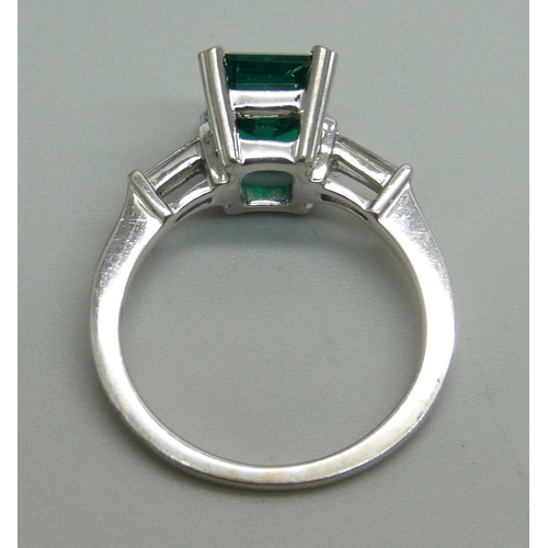 1163 - An 18ct white gold ring set with diamond shoulders and a synthetic emerald, 4.1g, L