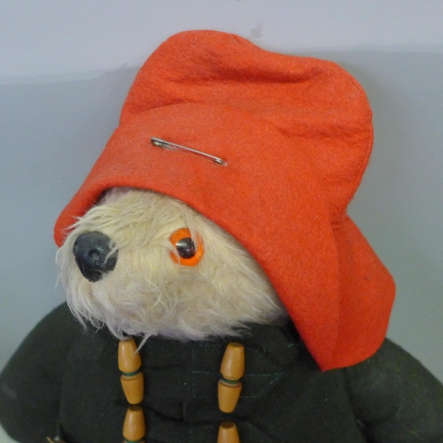 749 - A Paddington Bear soft toy, dark green duffel coat and red wellington boots