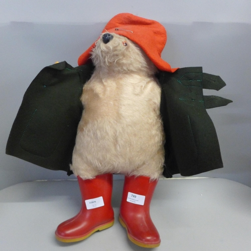 749 - A Paddington Bear soft toy, dark green duffel coat and red wellington boots