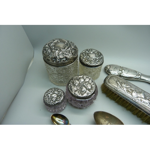 937 - Four silver topped dressing table jars, a silver hand mirror, silver spoons and a silver backed brus... 