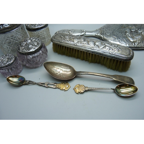 937 - Four silver topped dressing table jars, a silver hand mirror, silver spoons and a silver backed brus... 