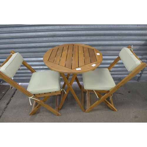 2253 - A teak circular folding garden table with a pair teak folding chairs and pastel green cushions