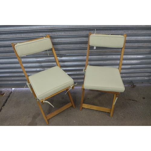 2253 - A teak circular folding garden table with a pair teak folding chairs and pastel green cushions