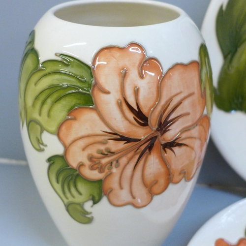 607 - Three items of Moorcroft Hibiscus pottery, a pair of plates and a vase, vase 18cm