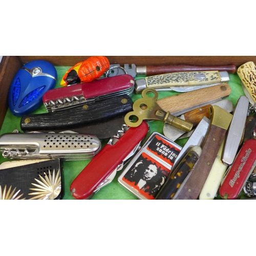 676 - A hinged display box of penknives, lighters, etc.