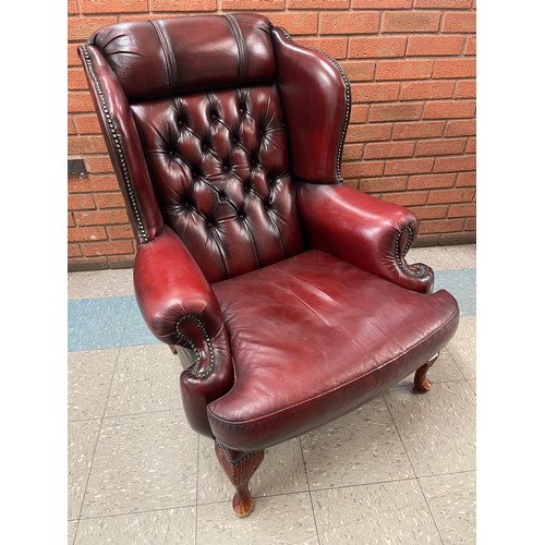 107 - An oxblood red leather wingback armchair