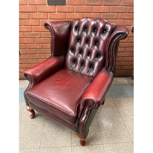105 - An oxblood red leather wingback armchair