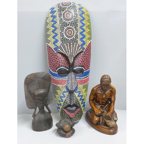 846 - A tribal hardwood head and a painted face mask, a small seated Buddha figure and a carved resin figu... 