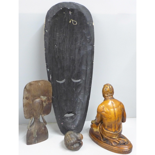 846 - A tribal hardwood head and a painted face mask, a small seated Buddha figure and a carved resin figu... 