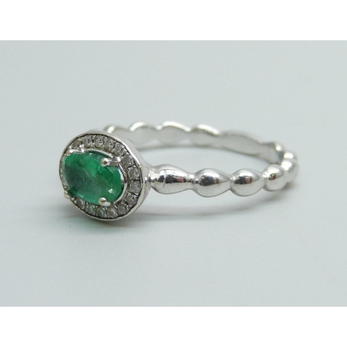 944 - A 14k white gold Zambian emerald and diamond ring, diamond 0.10 carat, emerald 0.45 carat