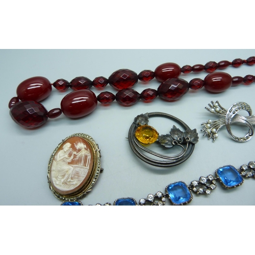 954 - A sherry amber coloured bead necklace, a charm bracelet, three brooches, etc.