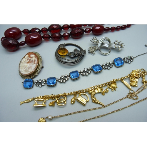 954 - A sherry amber coloured bead necklace, a charm bracelet, three brooches, etc.