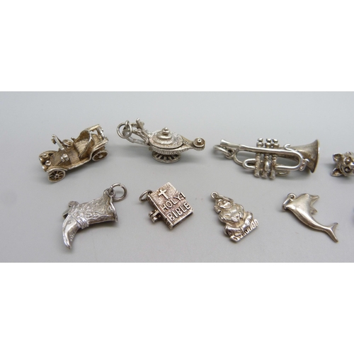 1052 - Twelve silver and white metal charms including a trumpet, a cat, a car etc., 43g