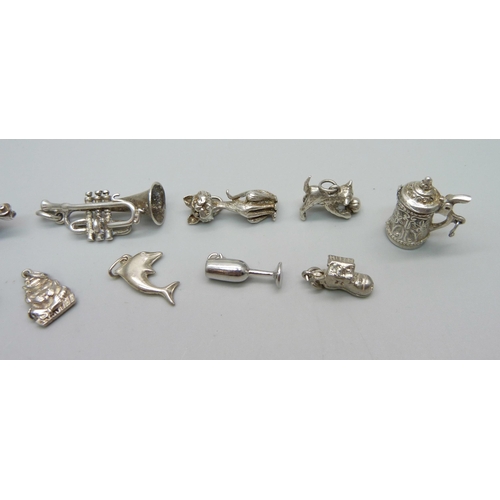 1052 - Twelve silver and white metal charms including a trumpet, a cat, a car etc., 43g