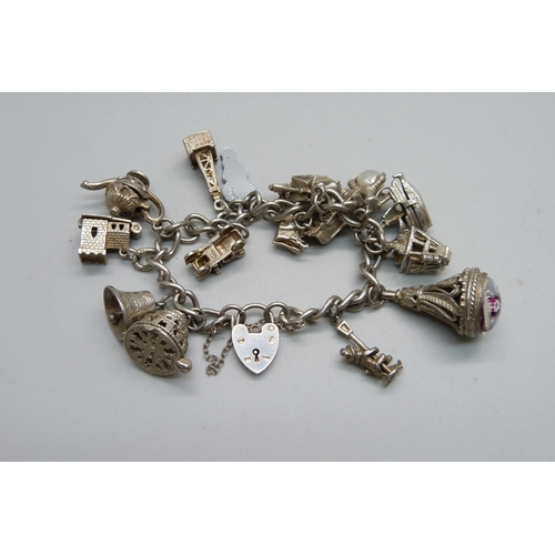 1064 - A silver charm bracelet with 14 silver and white metal charms, 67g