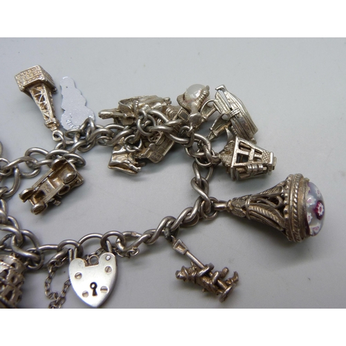 1064 - A silver charm bracelet with 14 silver and white metal charms, 67g