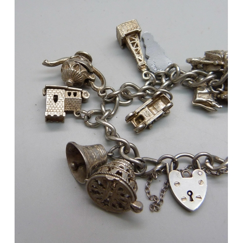 1064 - A silver charm bracelet with 14 silver and white metal charms, 67g