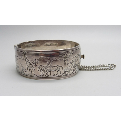 970 - A white metal bangle with African wild life detail, marked Wildtuin, Kruger Park, tests as silver, 6... 