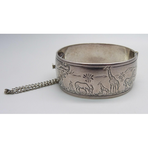 970 - A white metal bangle with African wild life detail, marked Wildtuin, Kruger Park, tests as silver, 6... 