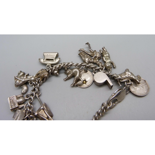 979 - A silver charm bracelet, with approximately 26 silver and white metal charms including 9 animals, 94... 