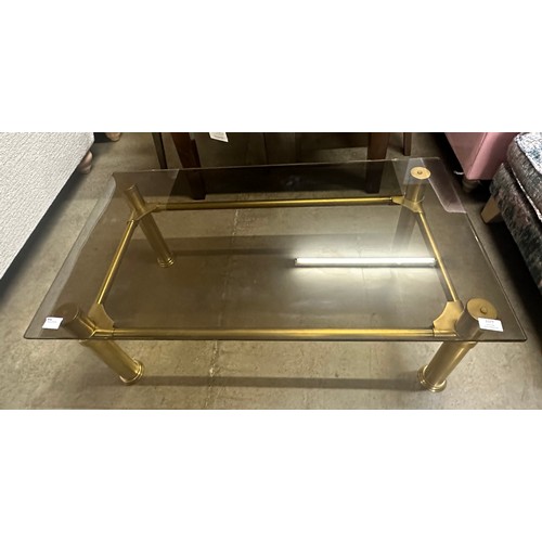 1377 - An oblong coffee table, toughened smoked glass with solid brass legs