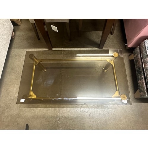 1377 - An oblong coffee table, toughened smoked glass with solid brass legs