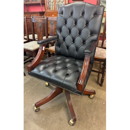 129 - A mahogany and black leather revolving desk chair