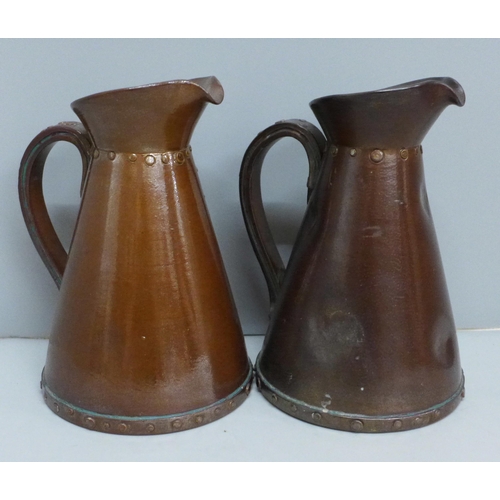 609 - A pair of Royal Doulton stoneware copper lustre jugs, realistically modelled as copper flagons with ... 