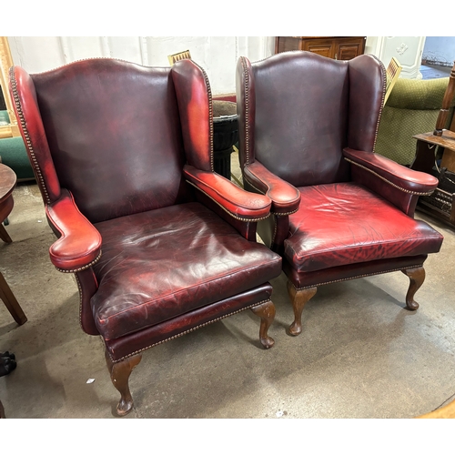 248 - A pair of oxblood red leather wing back armchairs