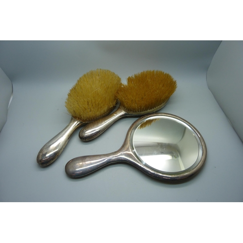 949 - Two silver backed brushes and a hand mirror