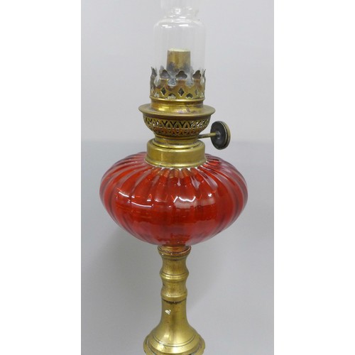 792 - A brass oil lamp with cranberry glass reservoir