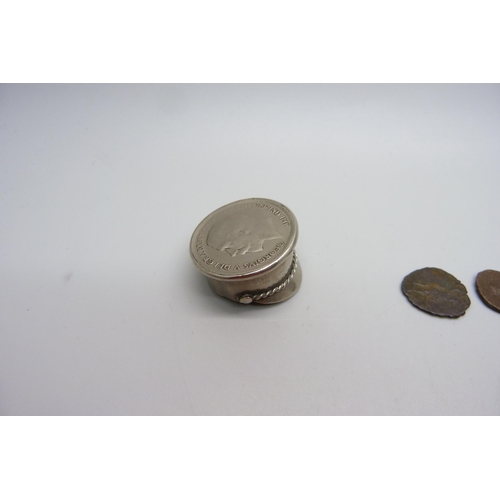 1069 - A small novelty peaked cap set with a one penny coin and three Roman coins