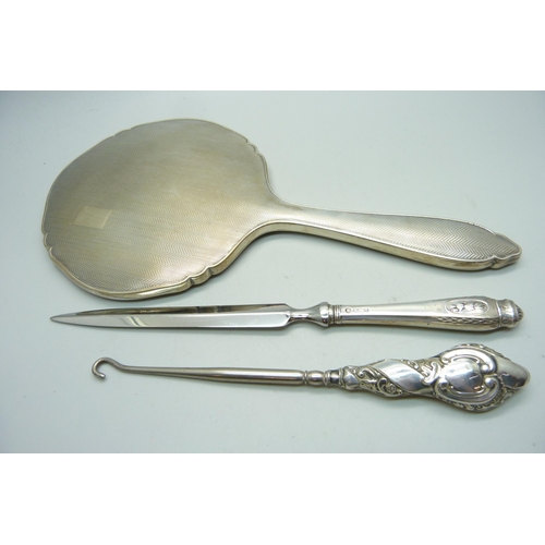 1072 - A silver backed hand mirror, a letter opener and a button hook