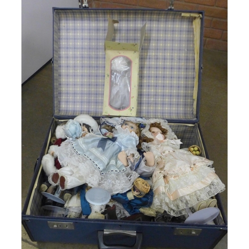 1124 - A box of modern porcelain dolls with display stands and one boxed baby crawling doll in a blue case ... 