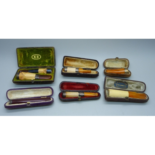 871 - Seven cheroot holders, with amber or sherry amber stems, six with sliver bands/rims, all cased