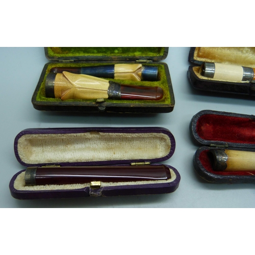 871 - Seven cheroot holders, with amber or sherry amber stems, six with sliver bands/rims, all cased