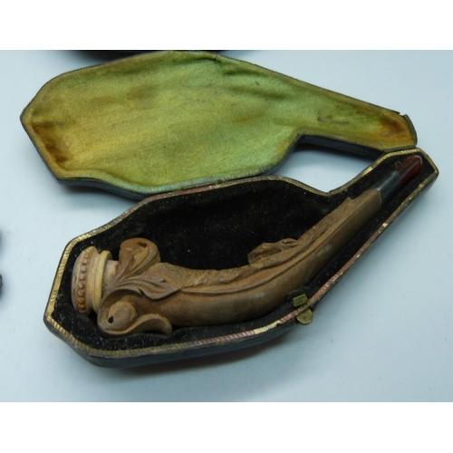 909 - Four Meerschaum pipes with amber stems, cased, one a/f