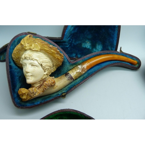 909 - Four Meerschaum pipes with amber stems, cased, one a/f