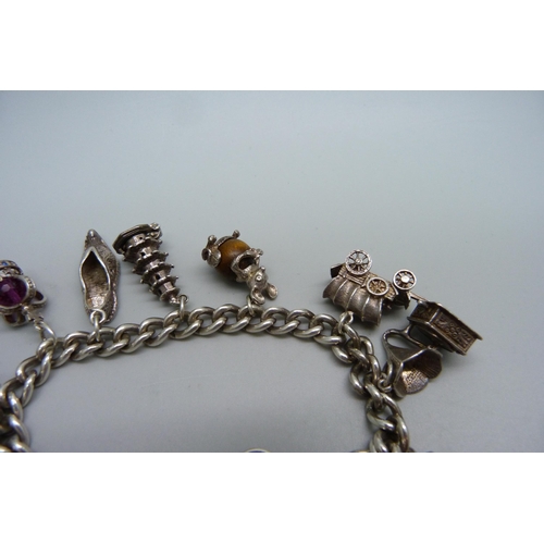 928 - A silver charm bracelet with ten silver charms, 63g