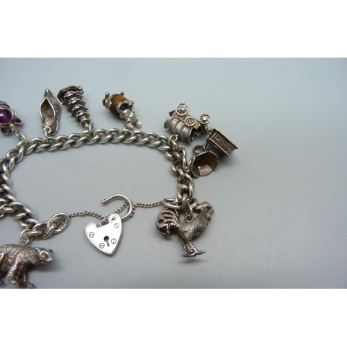 928 - A silver charm bracelet with ten silver charms, 63g