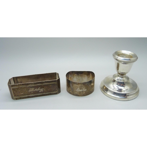 944 - Two silver napkin rings, 71g, and a small silver candlestick