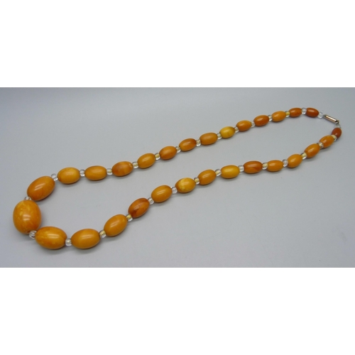 973 - A butterscotch amber graduated bead necklace interspersed with clear beads on a 9ct gold clasp, 23.4... 