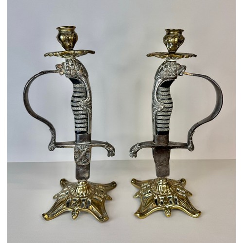 119 - A pair of brass mounted military sword handle candlesticks, 27cms h